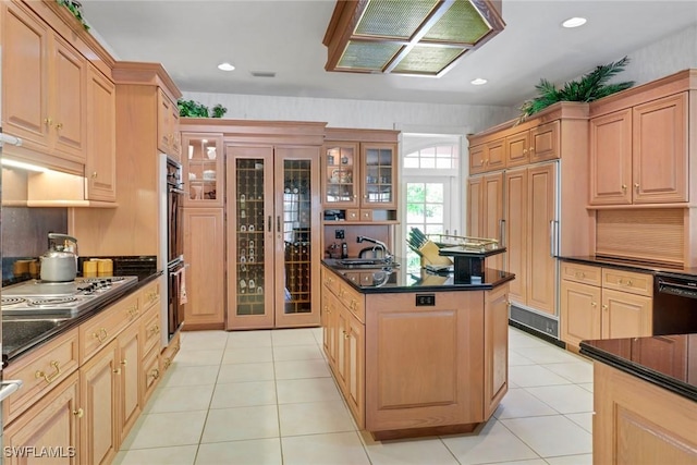 13488 Rosewood Ln, Naples, FL 34119 - kitchen featuring black appliances, a kitchen island, a sink, glass insert cabinets, and light tile patterned floors