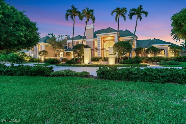 13488 Rosewood Ln, Naples, FL 34119 - view of front of property featuring stucco siding, a front lawn, and a chimney