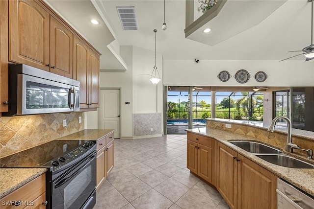 kitchen featuring stainless steel appliances, a sink, light stone countertops, decorative backsplash, and light tile patterned floors