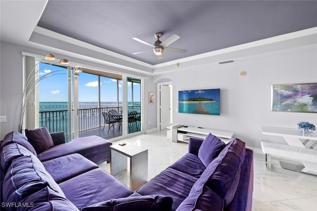 living area featuring a tray ceiling, marble finish floor, and baseboards