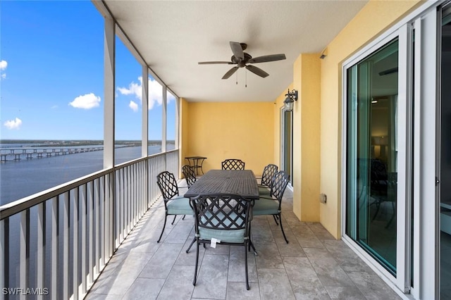 sunroom / solarium featuring a water view, outdoor dining space, and a ceiling fan