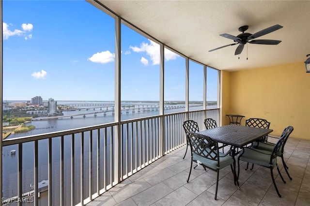 sunroom featuring a water view, a ceiling fan, and outdoor dining space