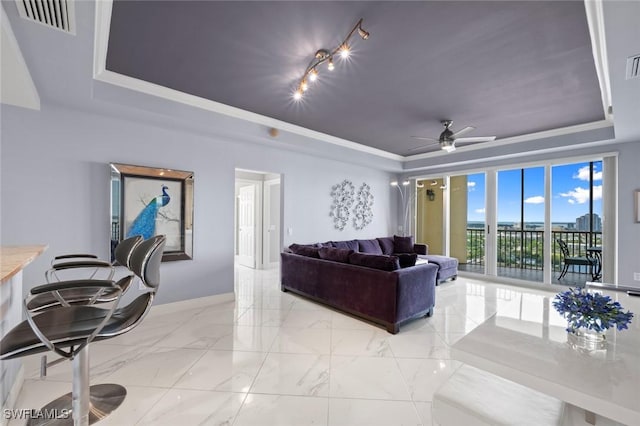 living room with a raised ceiling, ceiling fan, and visible vents