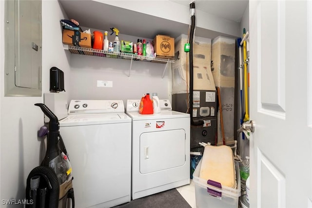 clothes washing area with independent washer and dryer, heating unit, light tile patterned floors, electric panel, and laundry area