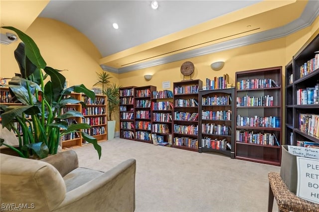living area with carpet flooring, wall of books, and vaulted ceiling
