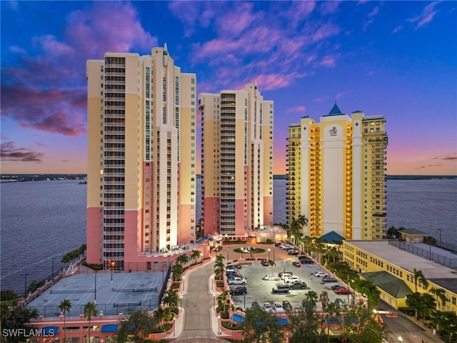property at dusk featuring a water view and a view of city