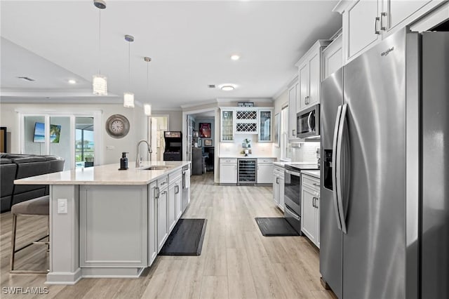 28140 Captiva Shell Loop, Bonita Springs, FL 34135 - kitchen featuring a sink, stainless steel appliances, crown molding, light wood finished floors, and beverage cooler