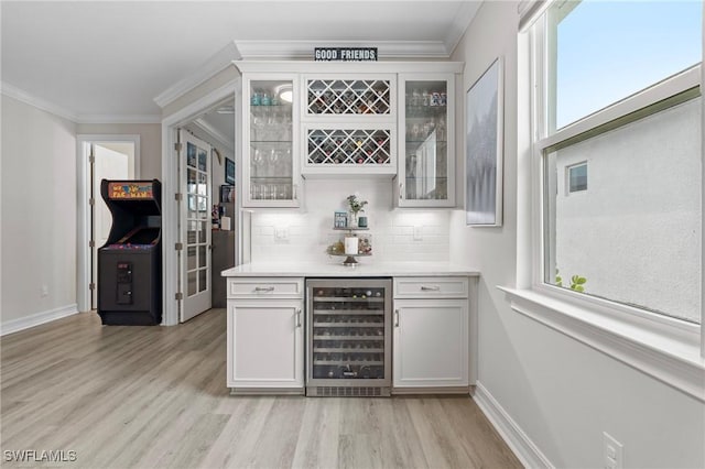 28140 Captiva Shell Loop, Bonita Springs, FL 34135 - bar with wine cooler, a dry bar, light wood-style flooring, crown molding, and tasteful backsplash