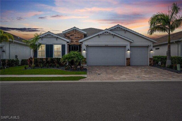 28140 Captiva Shell Loop, Bonita Springs, FL 34135 - view of front of house featuring a yard, an attached garage, stone siding, and driveway