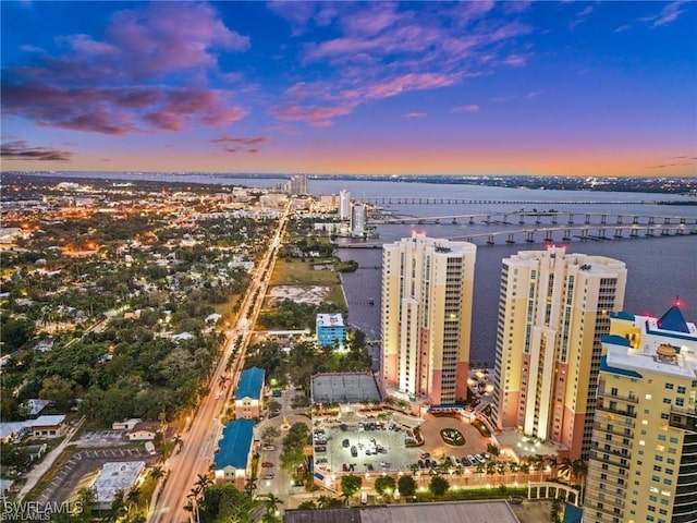 aerial view at dusk featuring a city view and a water view