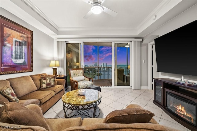 tiled living area featuring ornamental molding, a glass covered fireplace, and ceiling fan