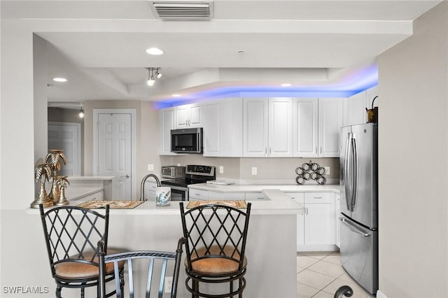 kitchen featuring a raised ceiling, visible vents, appliances with stainless steel finishes, and a kitchen bar