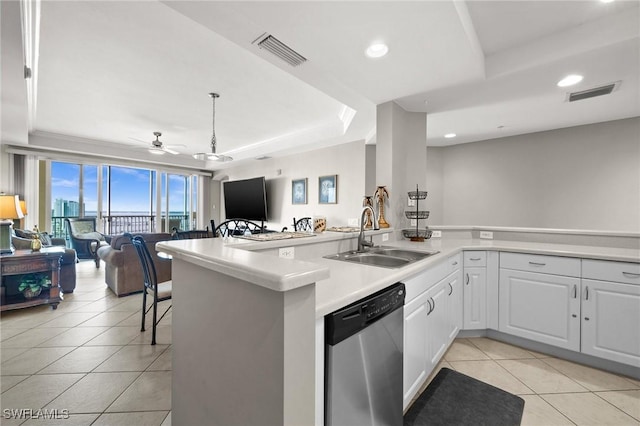 kitchen featuring a tray ceiling, dishwasher, visible vents, and a sink