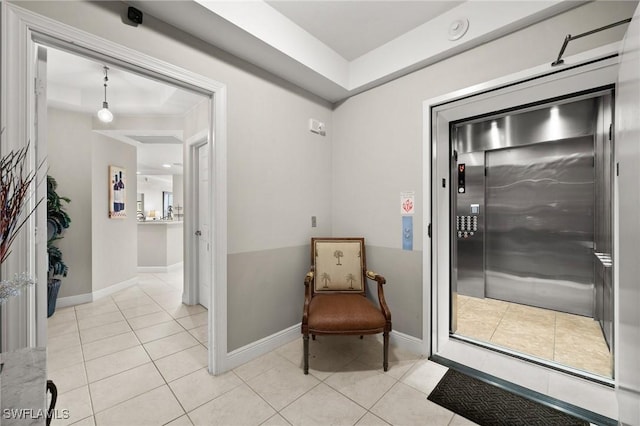 living area with elevator, light tile patterned floors, and baseboards