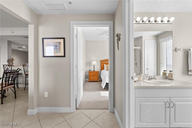 ensuite bathroom with vanity, visible vents, tile patterned floors, connected bathroom, and baseboards