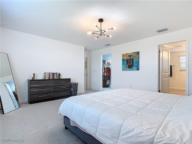 bedroom featuring a walk in closet, light colored carpet, visible vents, baseboards, and an inviting chandelier