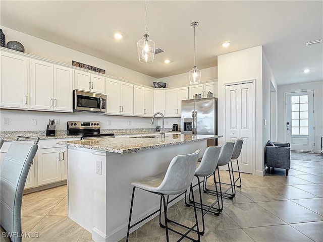 13868 Pine Lodge Ln, Fort Myers, FL 33913 - kitchen featuring stainless steel appliances, a sink, light stone countertops, an island with sink, and white cabinets