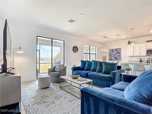 living room with light tile patterned flooring, a chandelier, recessed lighting, baseboards, and visible vents