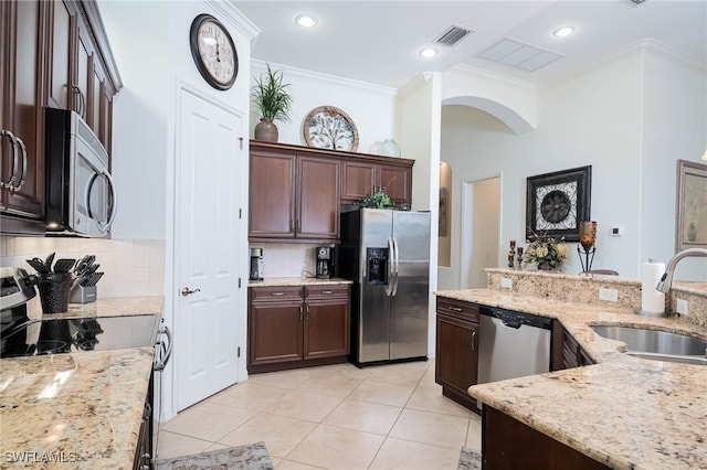 kitchen with a sink, ornamental molding, visible vents, arched walkways, and appliances with stainless steel finishes