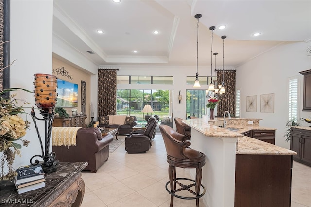 kitchen featuring a sink, recessed lighting, crown molding, a kitchen bar, and light tile patterned floors