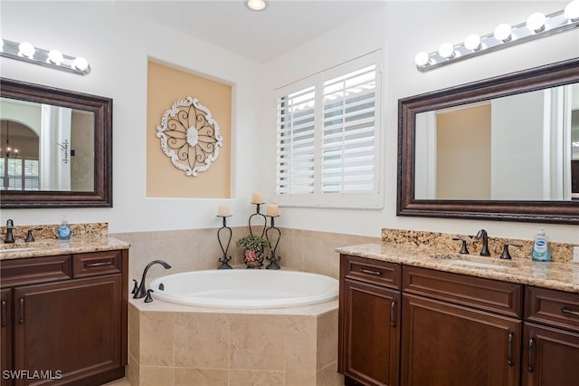 bathroom featuring a sink, two vanities, and a bath