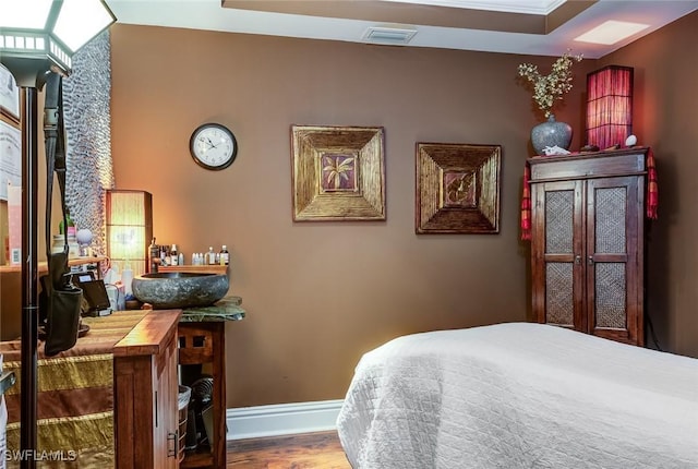 bedroom featuring baseboards, visible vents, and wood finished floors