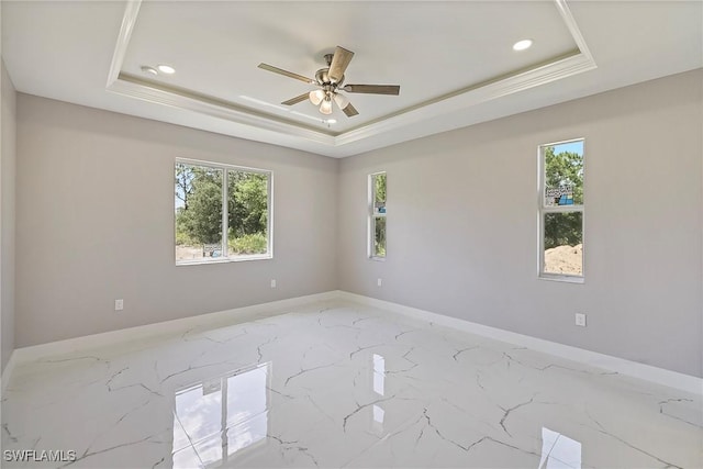 unfurnished room featuring baseboards, a ceiling fan, a tray ceiling, and marble finish floor