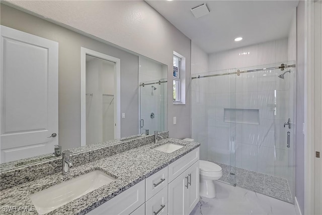 bathroom featuring double vanity, toilet, a sink, and a stall shower