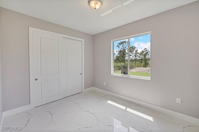 unfurnished bedroom featuring baseboards, a closet, and marble finish floor