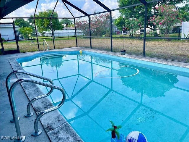 outdoor pool featuring a lanai, fence, and a lawn