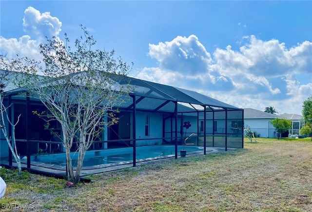 back of property featuring a yard, an outdoor pool, and a lanai
