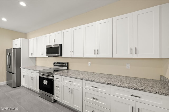 1043 Albert Ave, Lehigh Acres, FL 33971 - kitchen with light stone countertops, appliances with stainless steel finishes, recessed lighting, white cabinetry, and light tile patterned floors