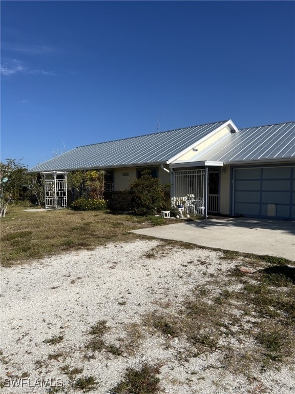 exterior space with a standing seam roof, an attached garage, driveway, and metal roof