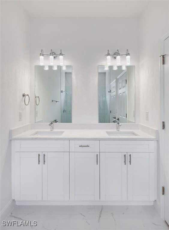 bathroom with double vanity, a sink, marble finish floor, and baseboards