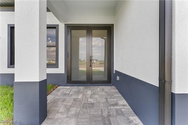 view of exterior entry featuring stucco siding and french doors