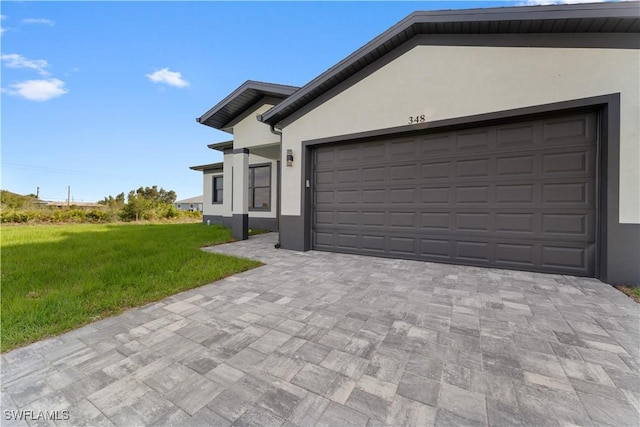 view of front of home with a garage, stucco siding, decorative driveway, and a front yard