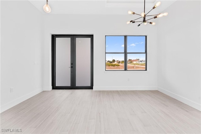 unfurnished room featuring baseboards, light wood-type flooring, and a chandelier