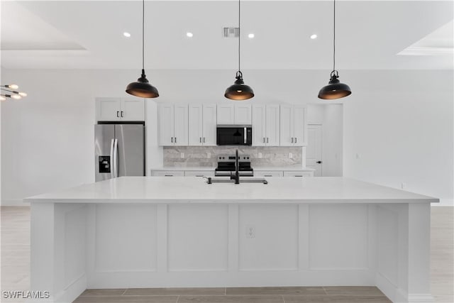 kitchen with a large island, light countertops, white cabinetry, tasteful backsplash, and appliances with stainless steel finishes