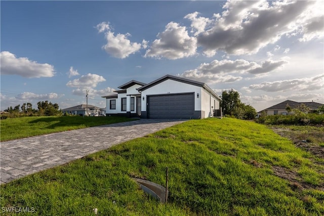 ranch-style home with an attached garage, stucco siding, a front yard, decorative driveway, and central air condition unit