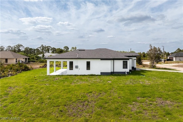 rear view of house with stucco siding, a yard, and a patio area