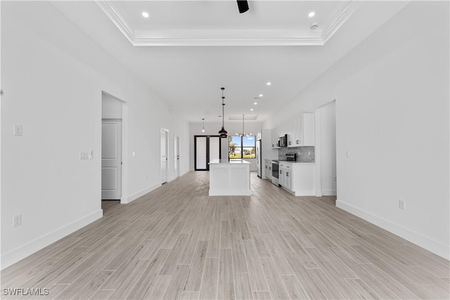 unfurnished living room with a raised ceiling, baseboards, and light wood-style flooring