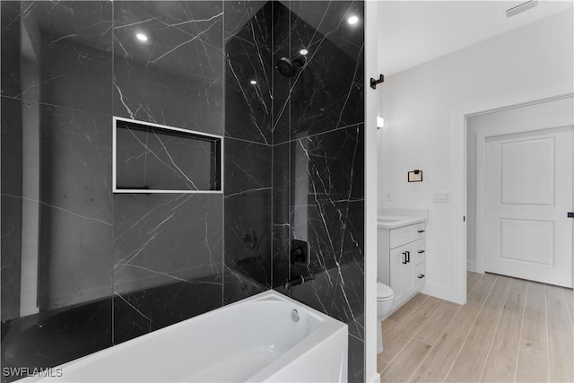 full bath with a bathtub, visible vents, wood finished floors, vanity, and toilet
