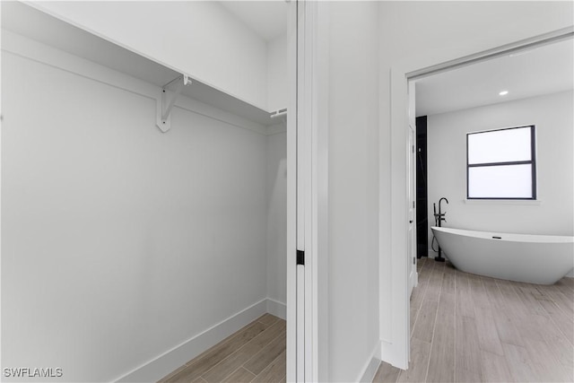 bathroom featuring baseboards, a soaking tub, and wood finished floors