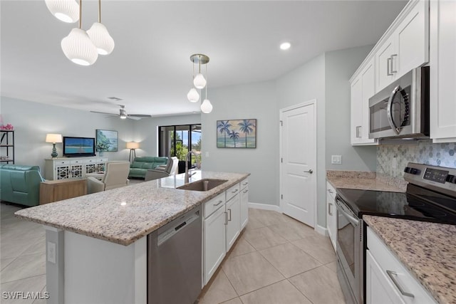 kitchen with white cabinets, open floor plan, appliances with stainless steel finishes, and a sink
