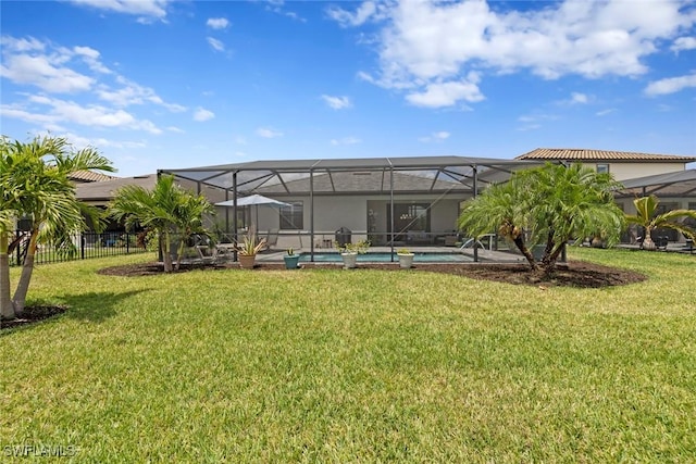 back of property with a lawn, an outdoor pool, and glass enclosure