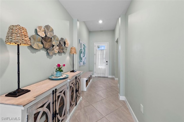 corridor featuring baseboards, light tile patterned floors, and recessed lighting