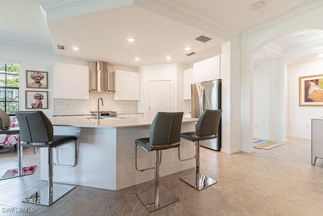 2173 Frangipani Cir Unit 102, Naples, FL 34120 - kitchen with freestanding refrigerator, wall chimney exhaust hood, ornamental molding, a breakfast bar, and white cabinets