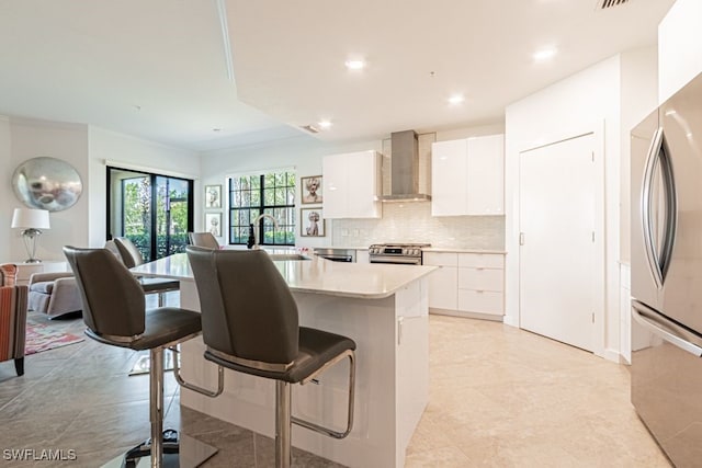 2173 Frangipani Cir Unit 102, Naples, FL 34120 - kitchen with wall chimney exhaust hood, stainless steel appliances, a sink, modern cabinets, and white cabinets