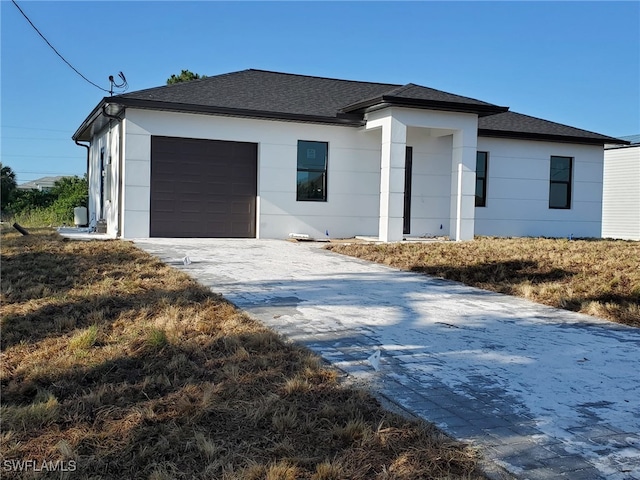 view of front of home featuring decorative driveway, a shingled roof, and a garage