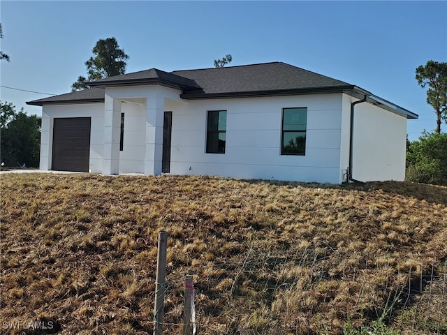 view of front of house with a garage, roof with shingles, and stucco siding